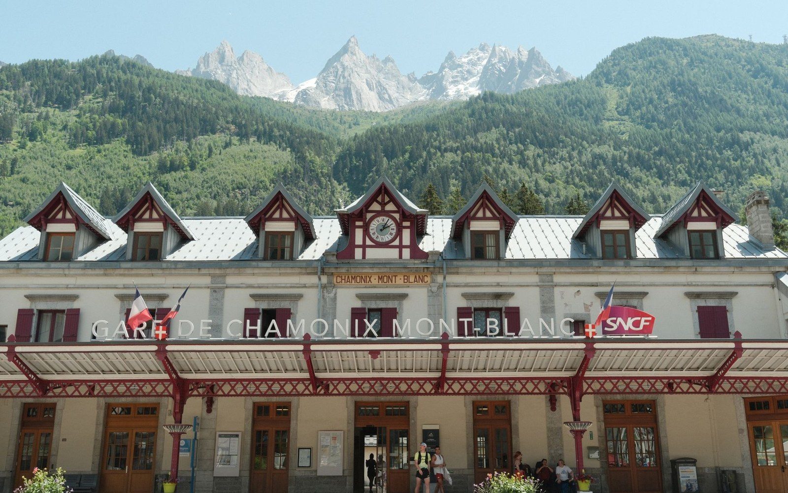 Chamonix Mont-Blanc train station with jagged mountain peaks rising behind its gabled roof