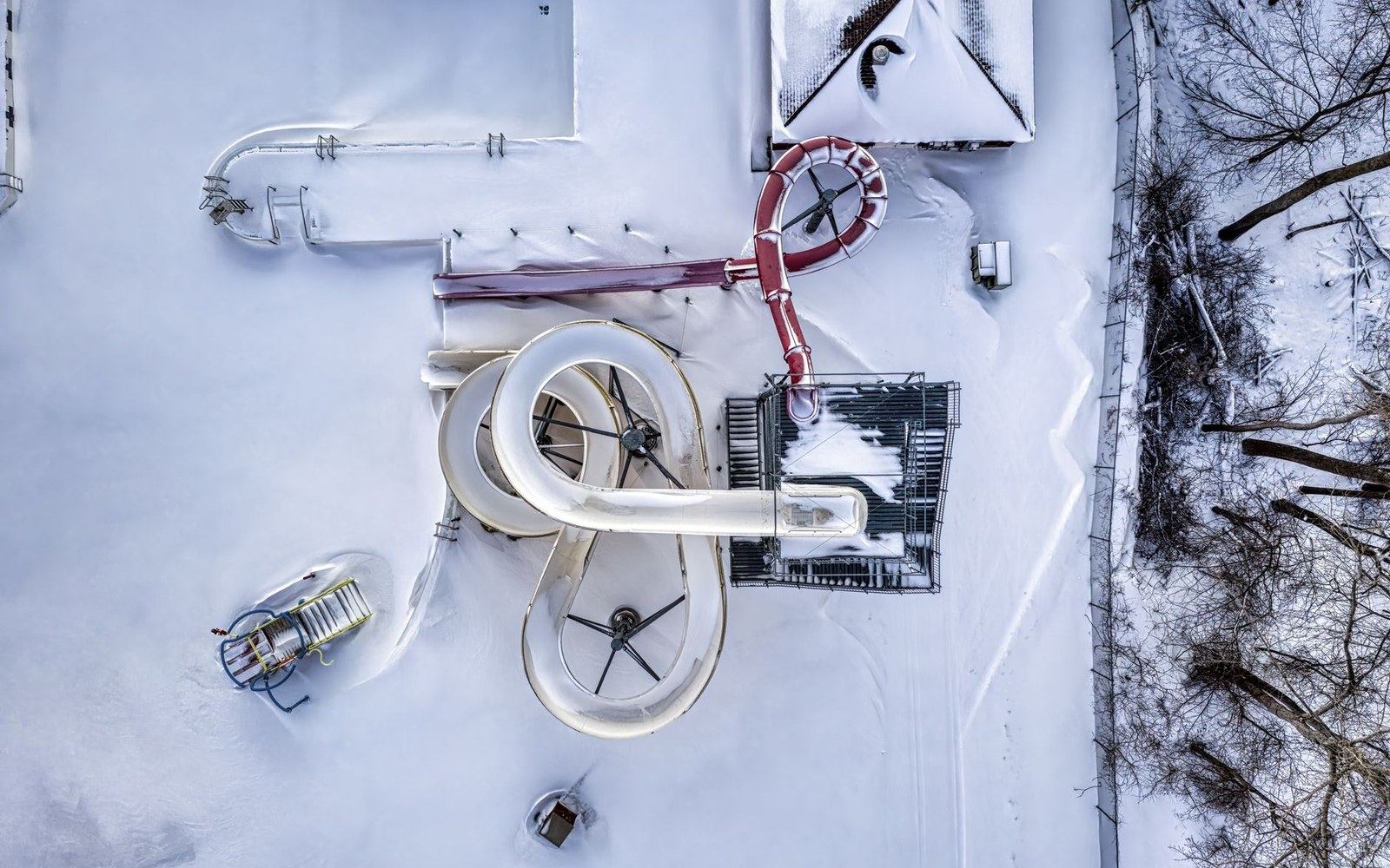 Aerial view of snow-covered water park slides coiling above a rooftop in winter